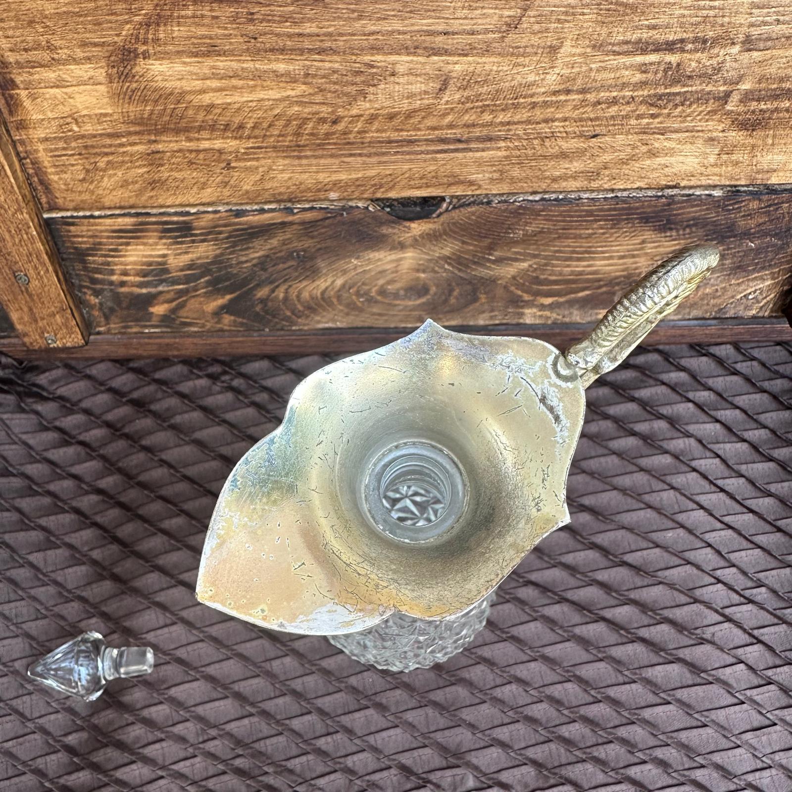Decorative glass object with a metal handle on a textured surface
