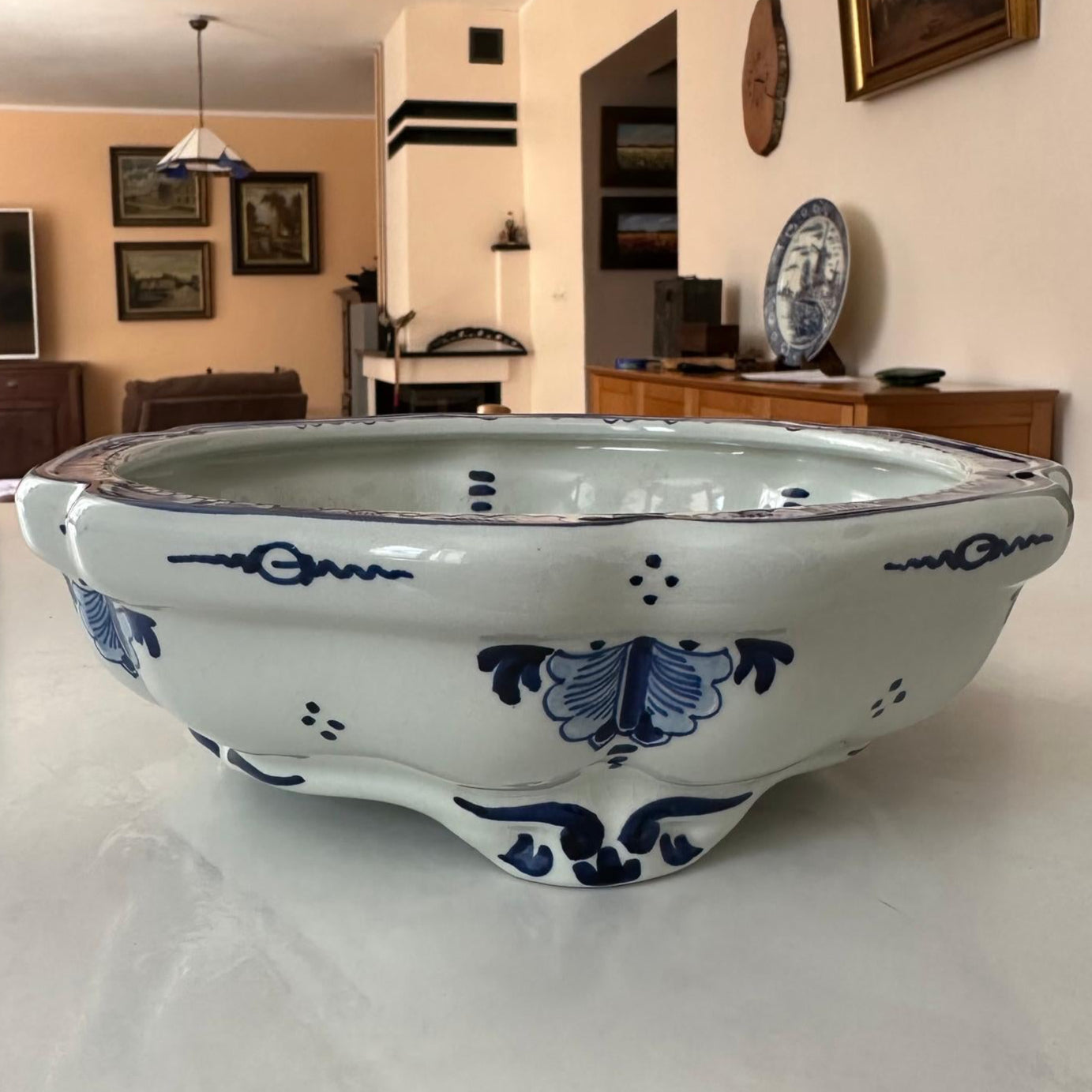 Decorative ceramic bowl with blue patterns on a white surface in a room setting.