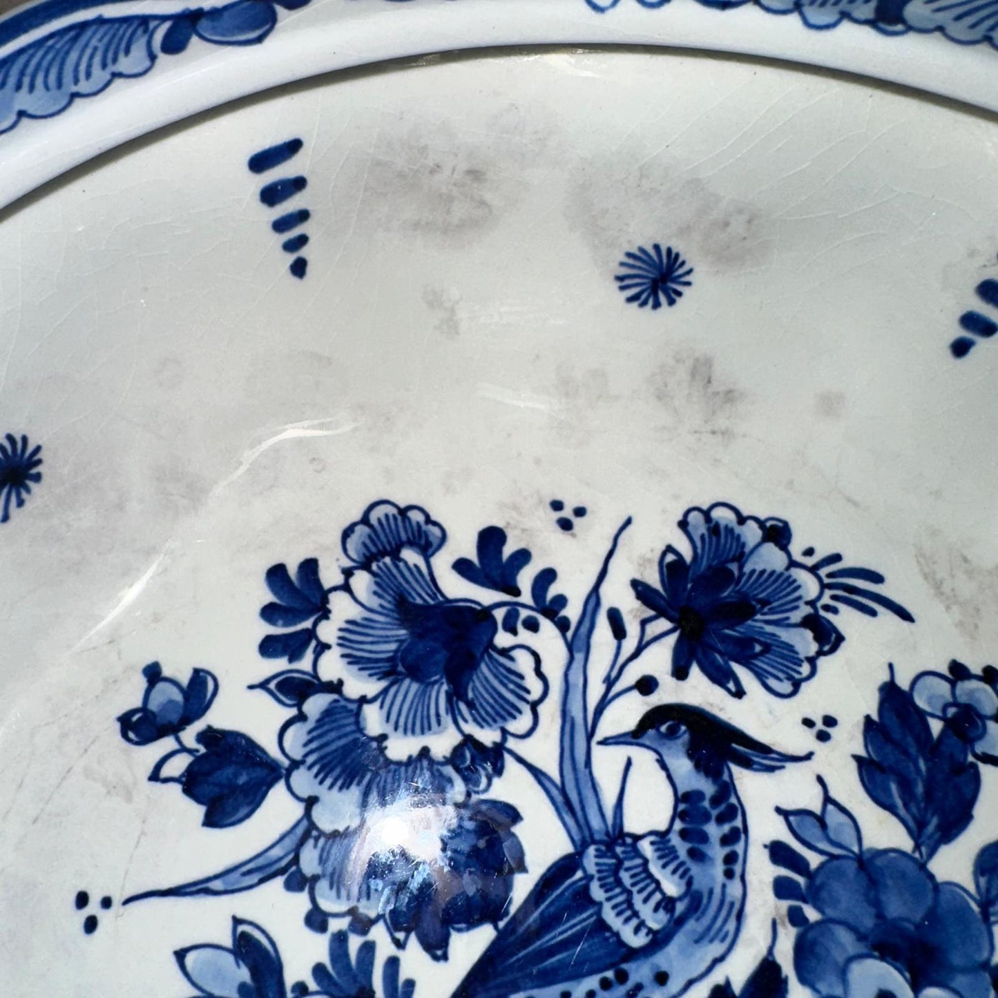 Close-up of a blue floral and bird design on a white ceramic plate.