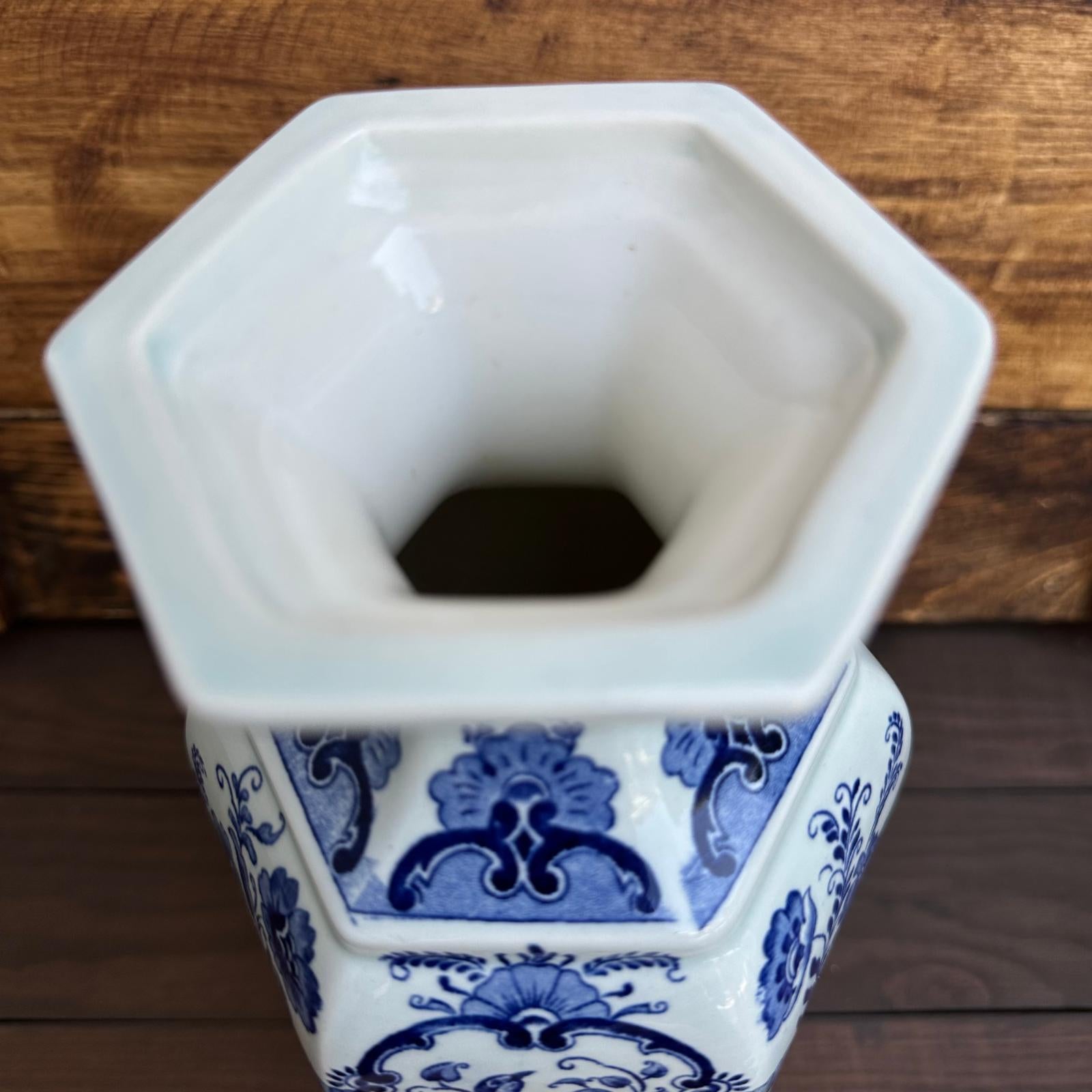 Hexagonal ceramic vase with blue and white patterns on a wooden surface