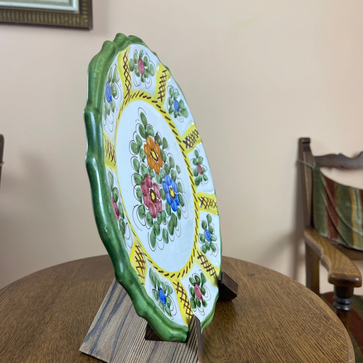 Decorative ceramic plate with floral patterns on a stand against a neutral background