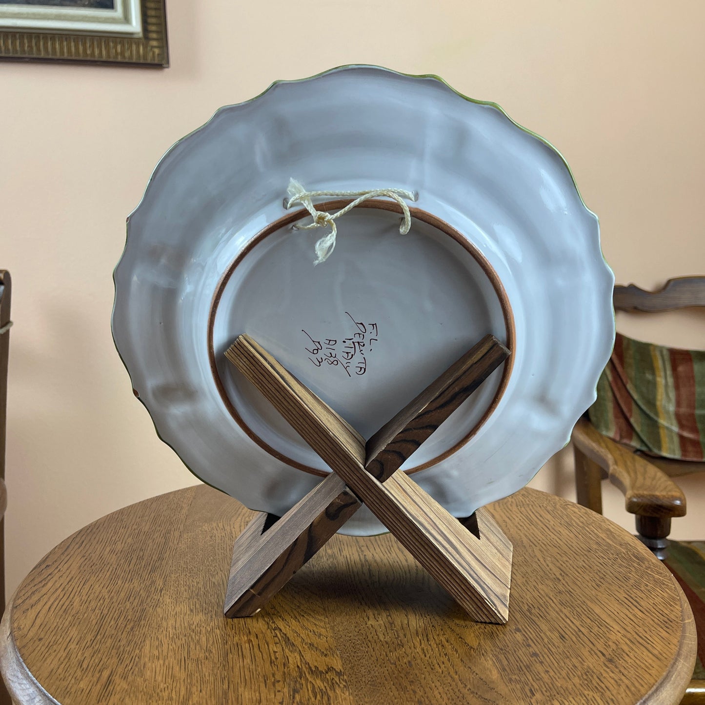 Light blue ceramic plate with scalloped edge on a wooden stand, against a neutral wall.