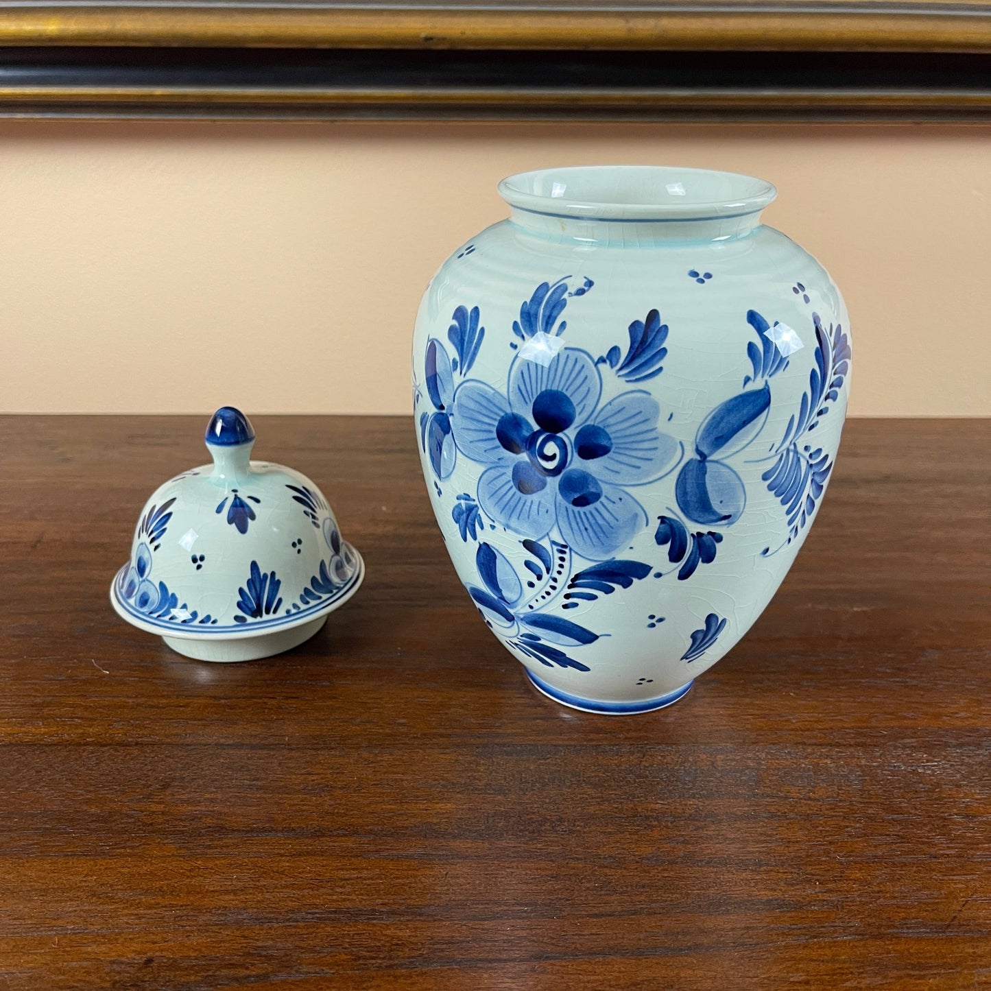 Blue and white floral-patterned ceramic jar and cover on a wooden surface.