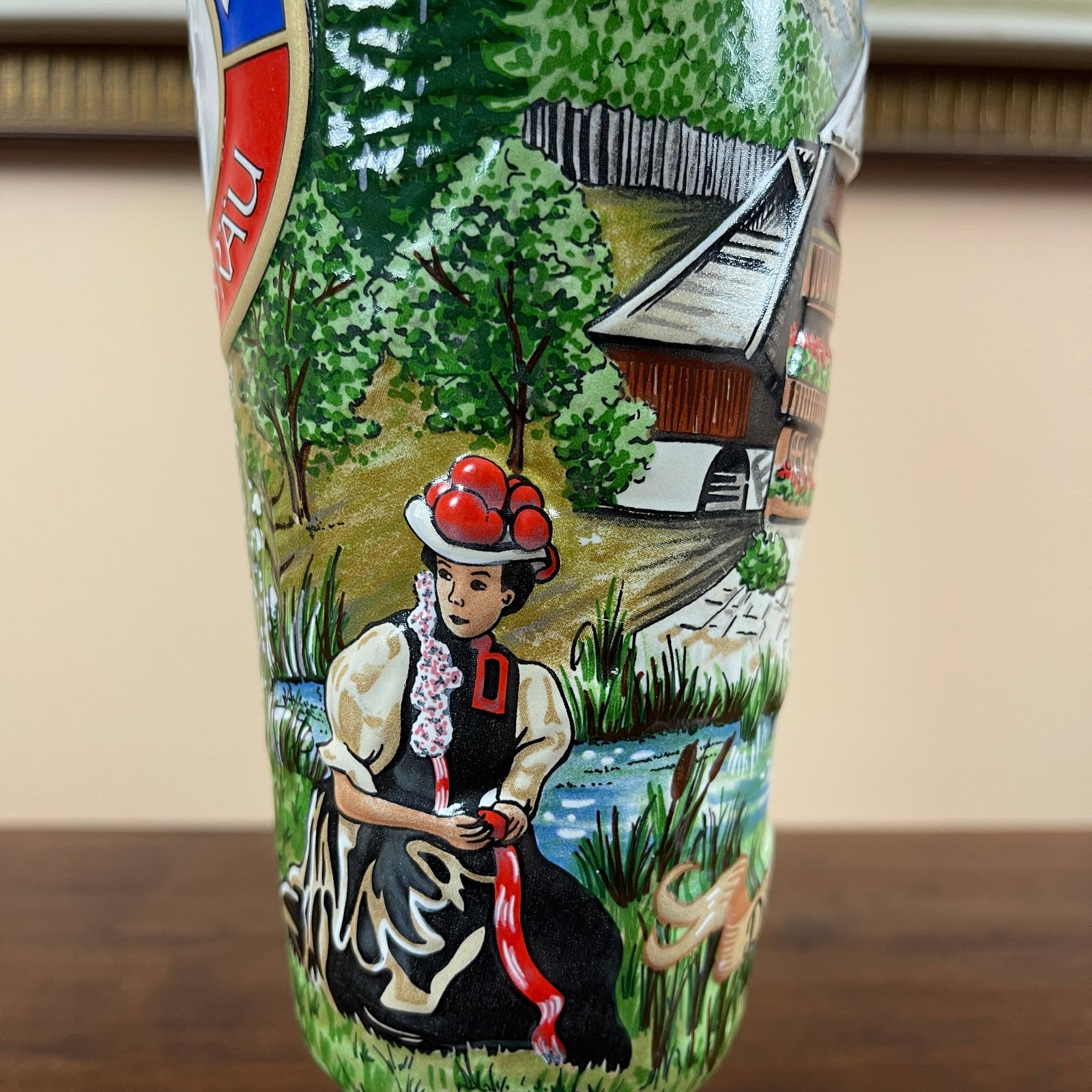 Decorative bottle with a painted design of a woman in traditional attire and landscape.