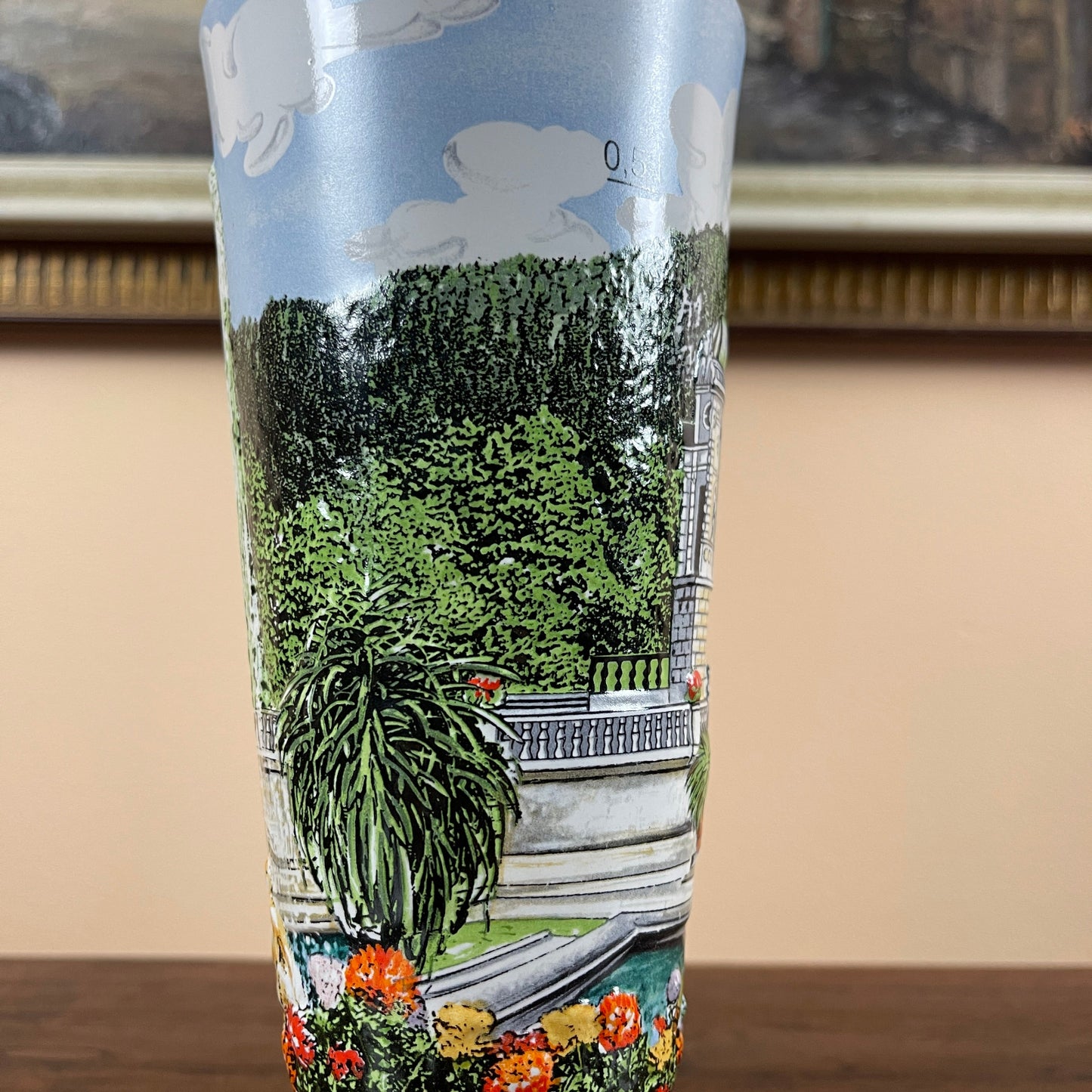 Tumbler with a scenic design of trees and flowers on a beige background
