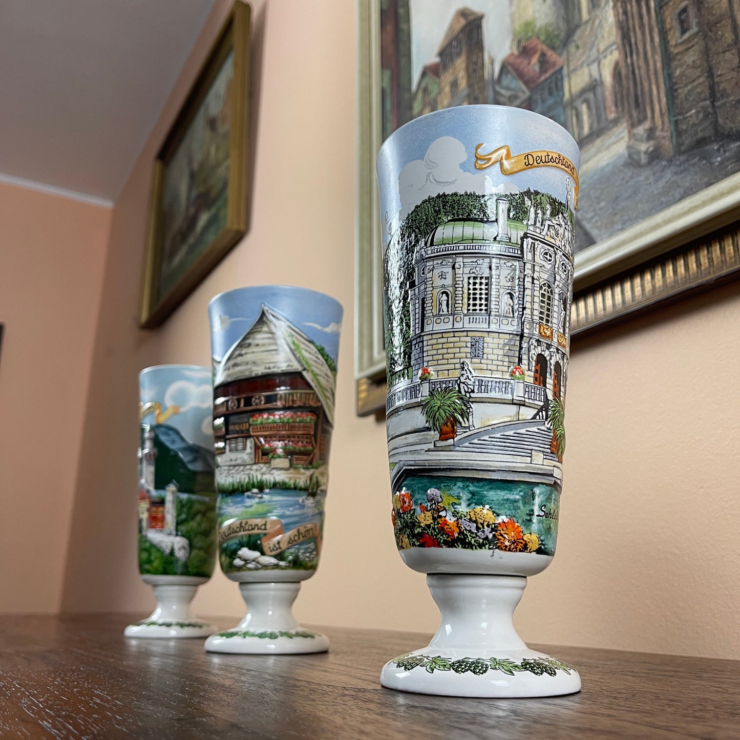 Three decorative glasses with architectural designs on a wooden surface.