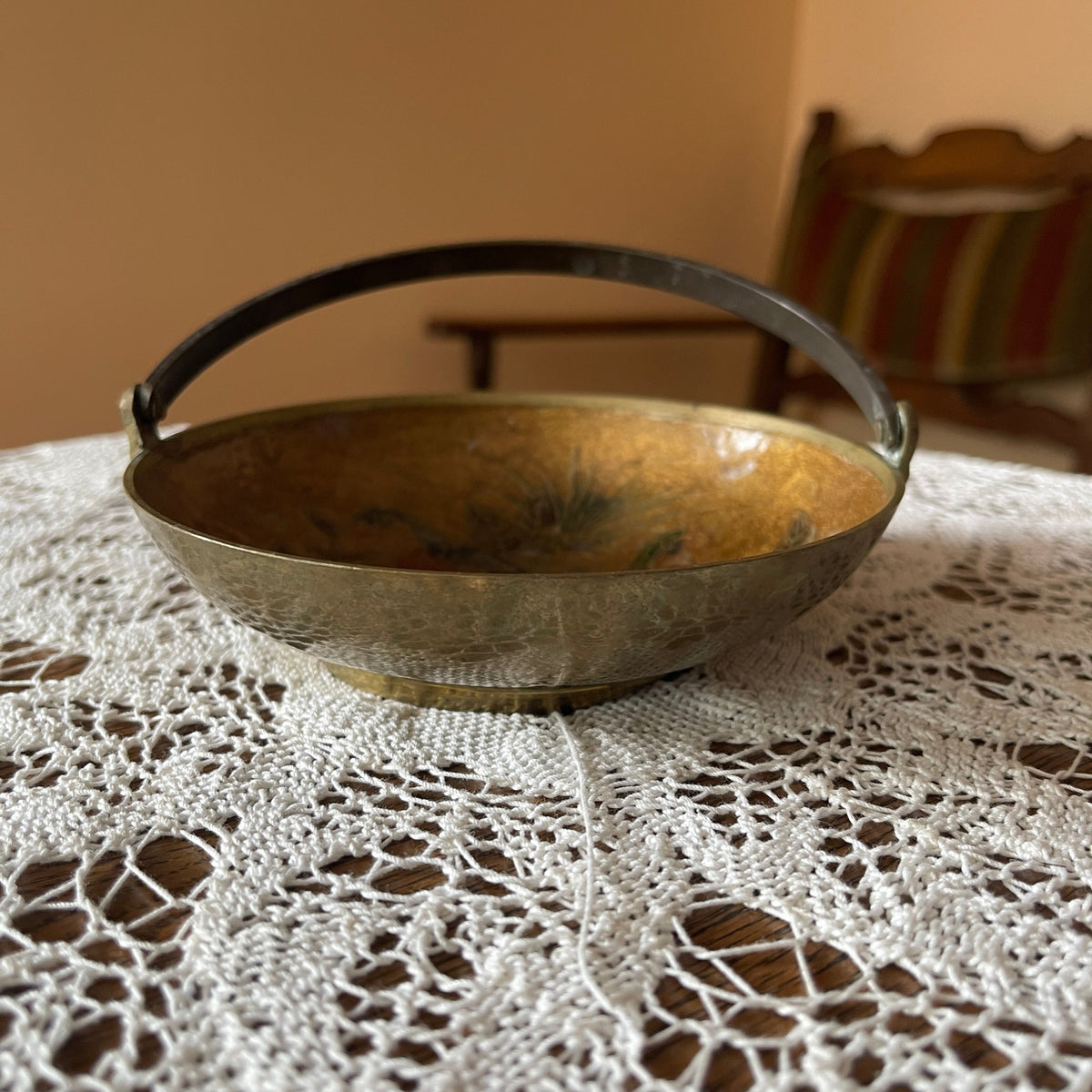 Bronze bowl with handle on a lace tablecloth