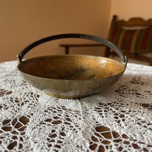 Bronze bowl with handle on a lace tablecloth