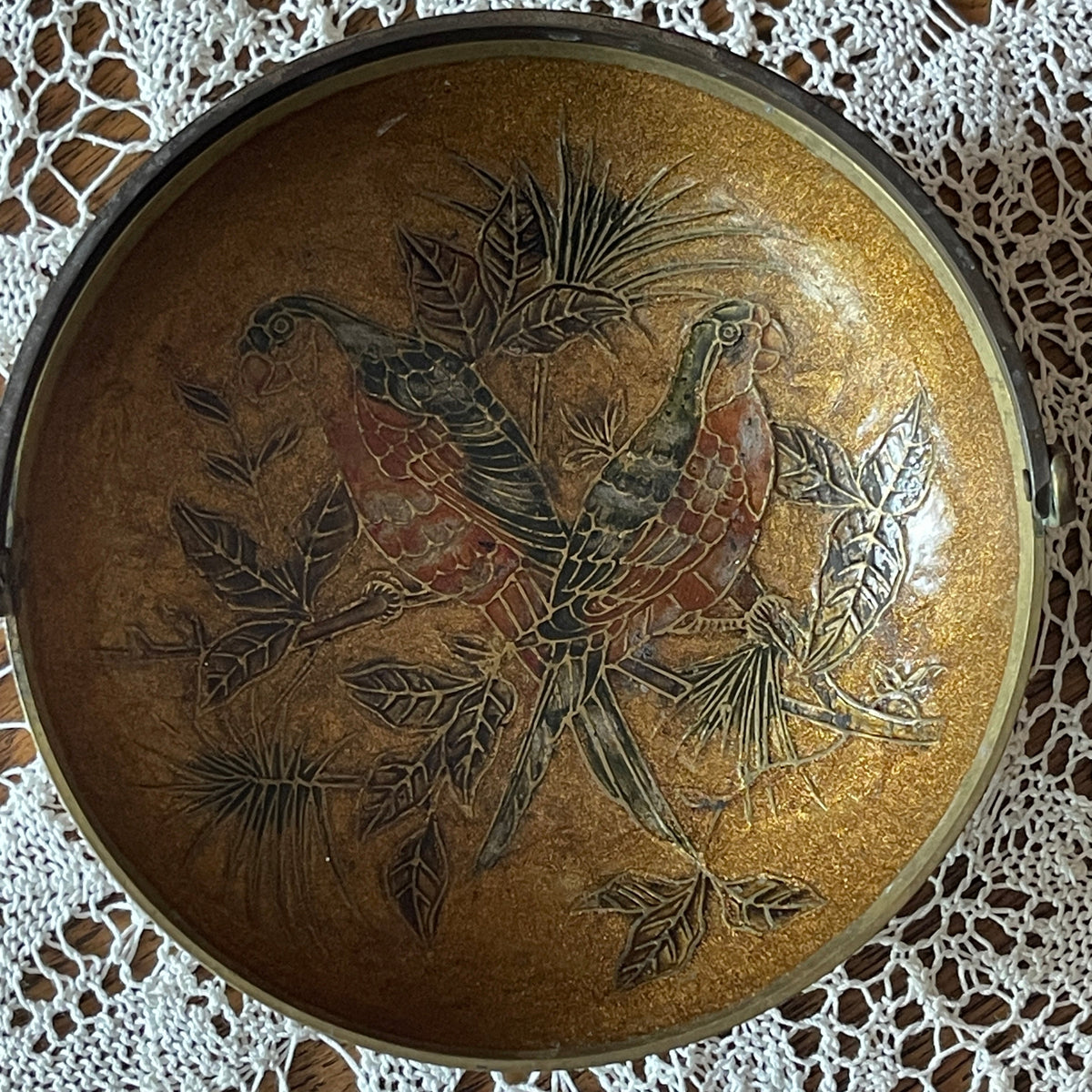 Decorative round object with parrot design on a lace background