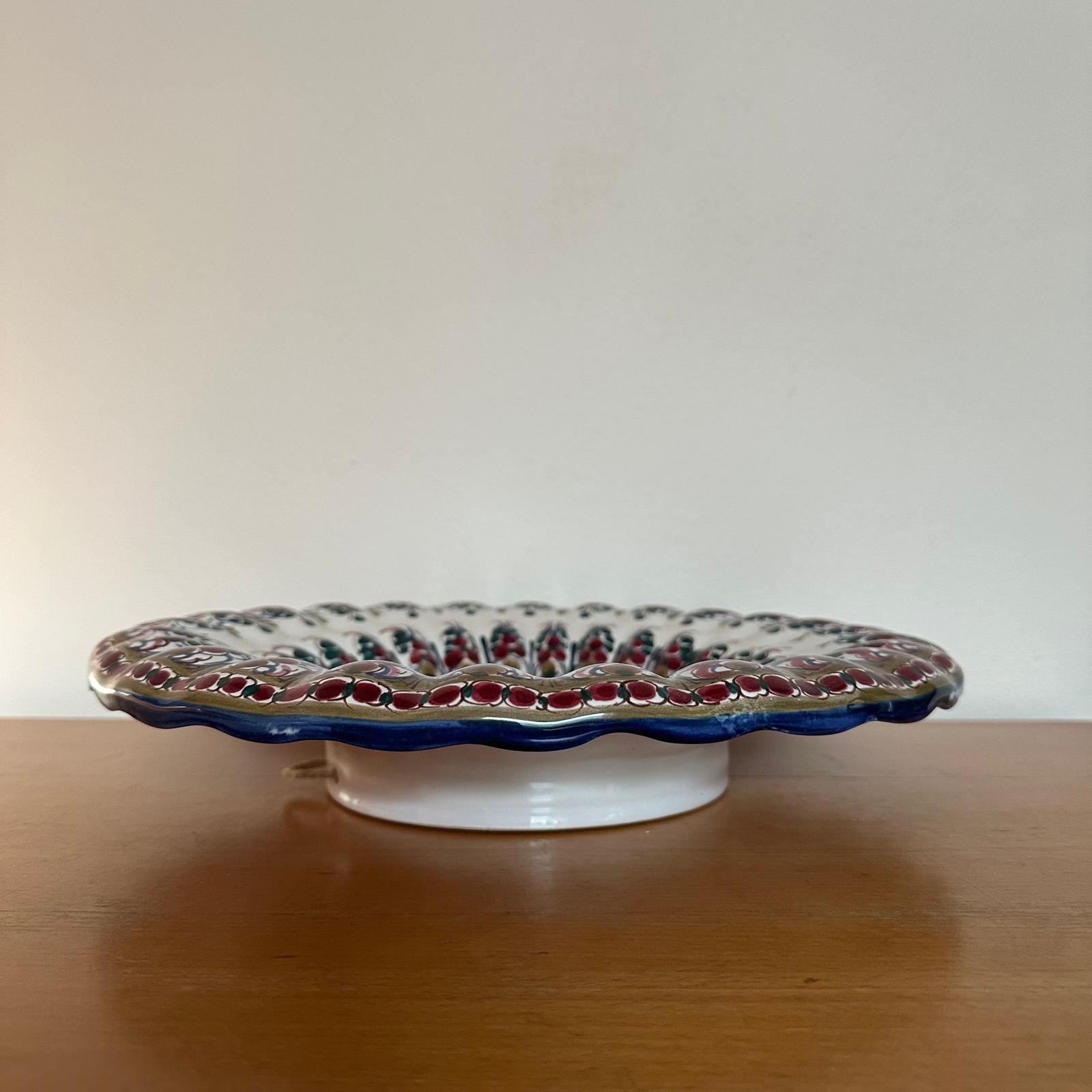 Decorative ceramic plate with scalloped edge on a wooden surface