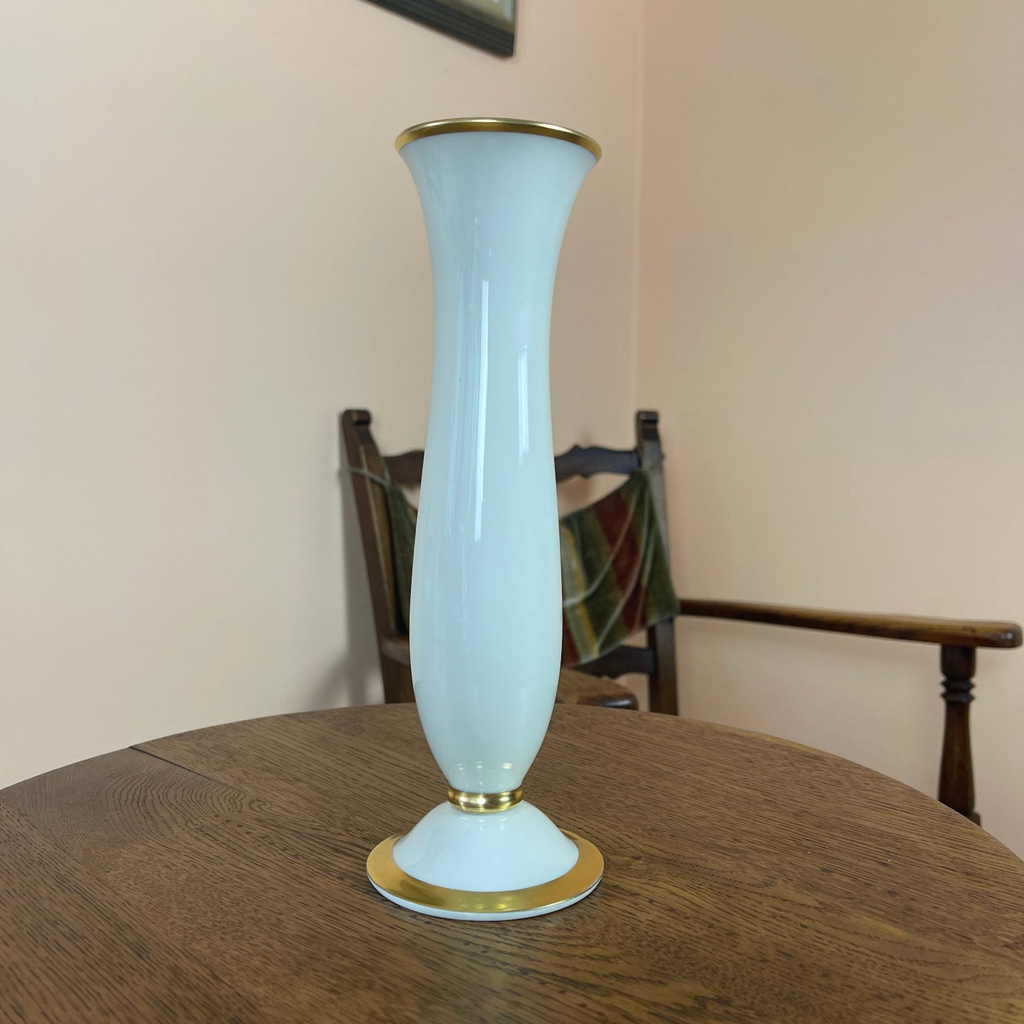 White vase with gold rim and base on a wooden table