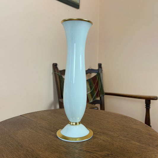 White vase with gold rim and base on a wooden table