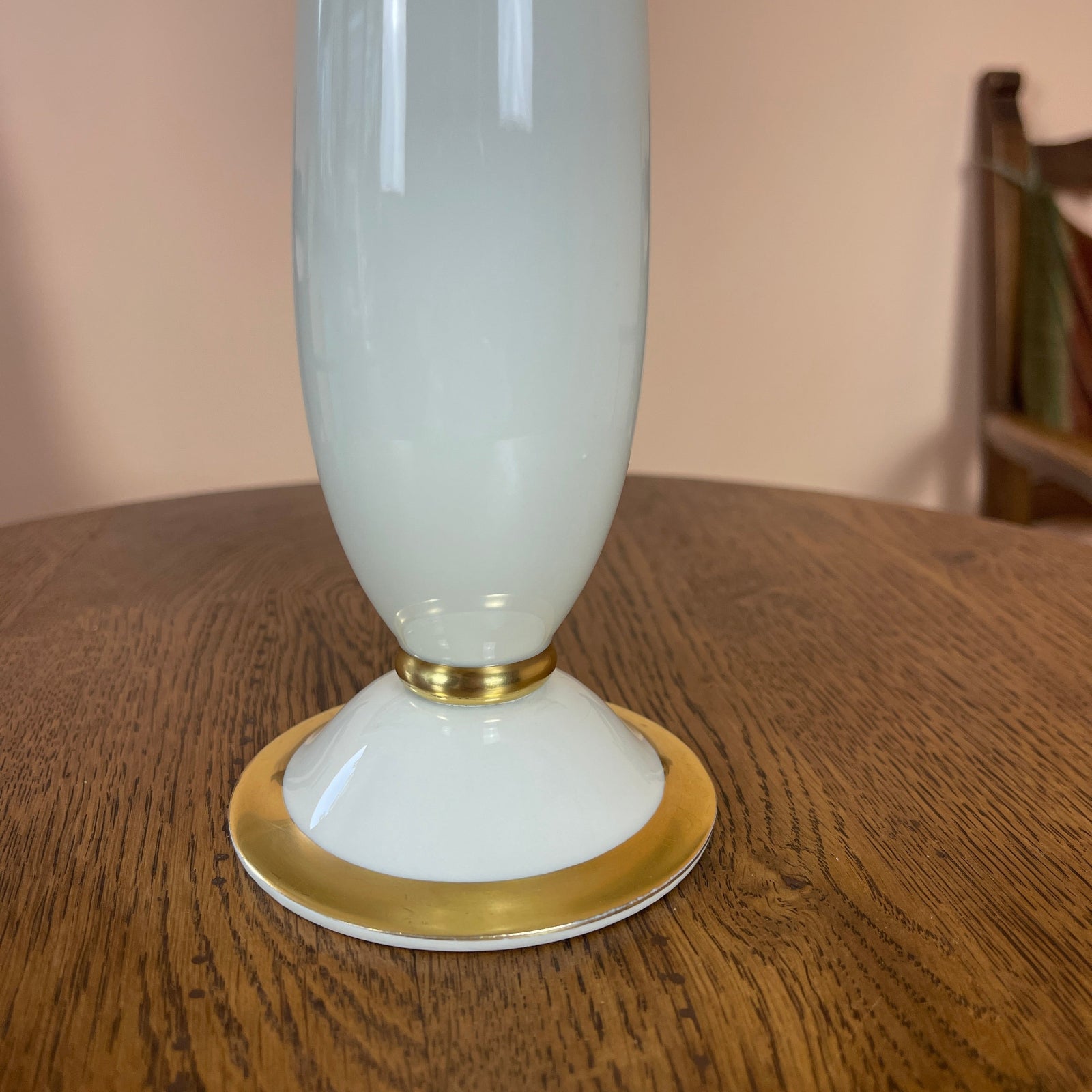 White vase with gold base on a wooden surface