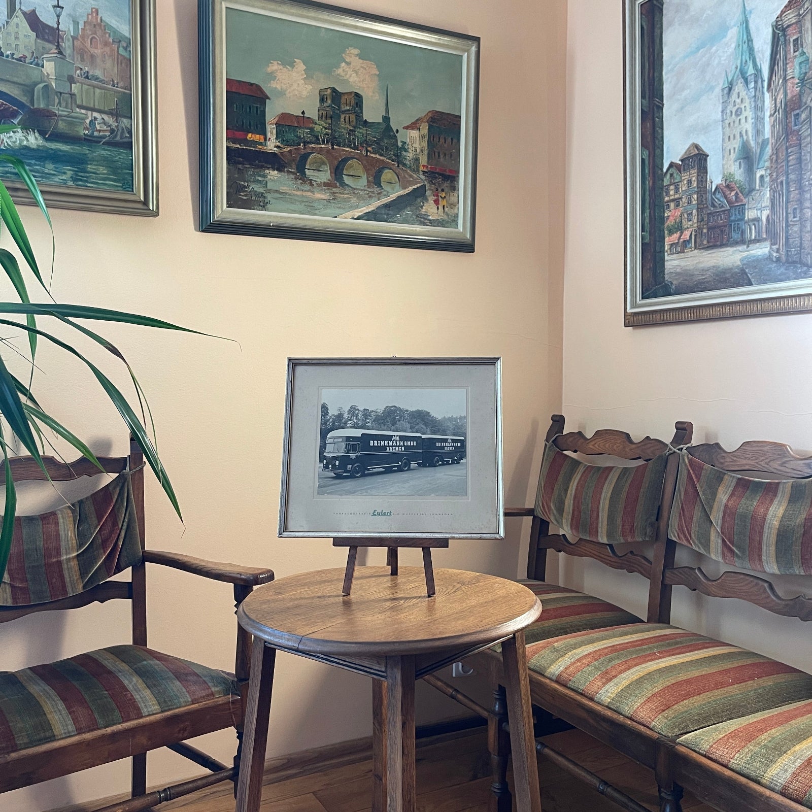 Room interior with wooden chairs, a small round table, and framed pictures on the wall.