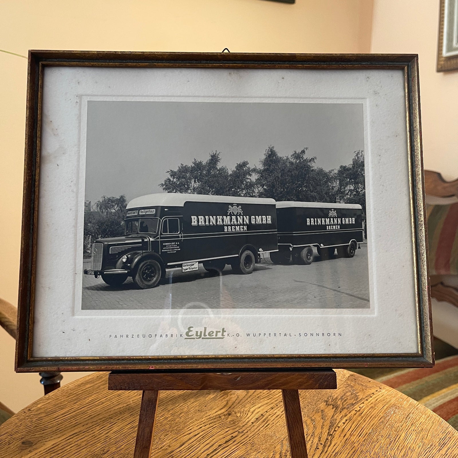Framed black and white photo of Brinkmann & Emre trucks on a wooden stand.