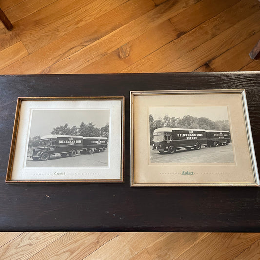 Two framed black and white photographs of buses on a wooden floor.