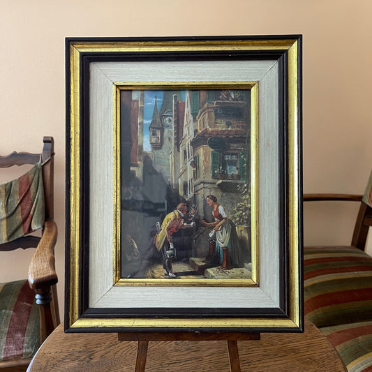 Framed painting of a couple in an urban setting on a wooden table.