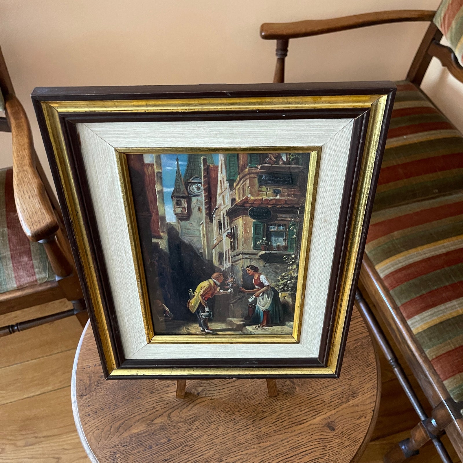 Framed painting of a street scene with people on a wooden table.