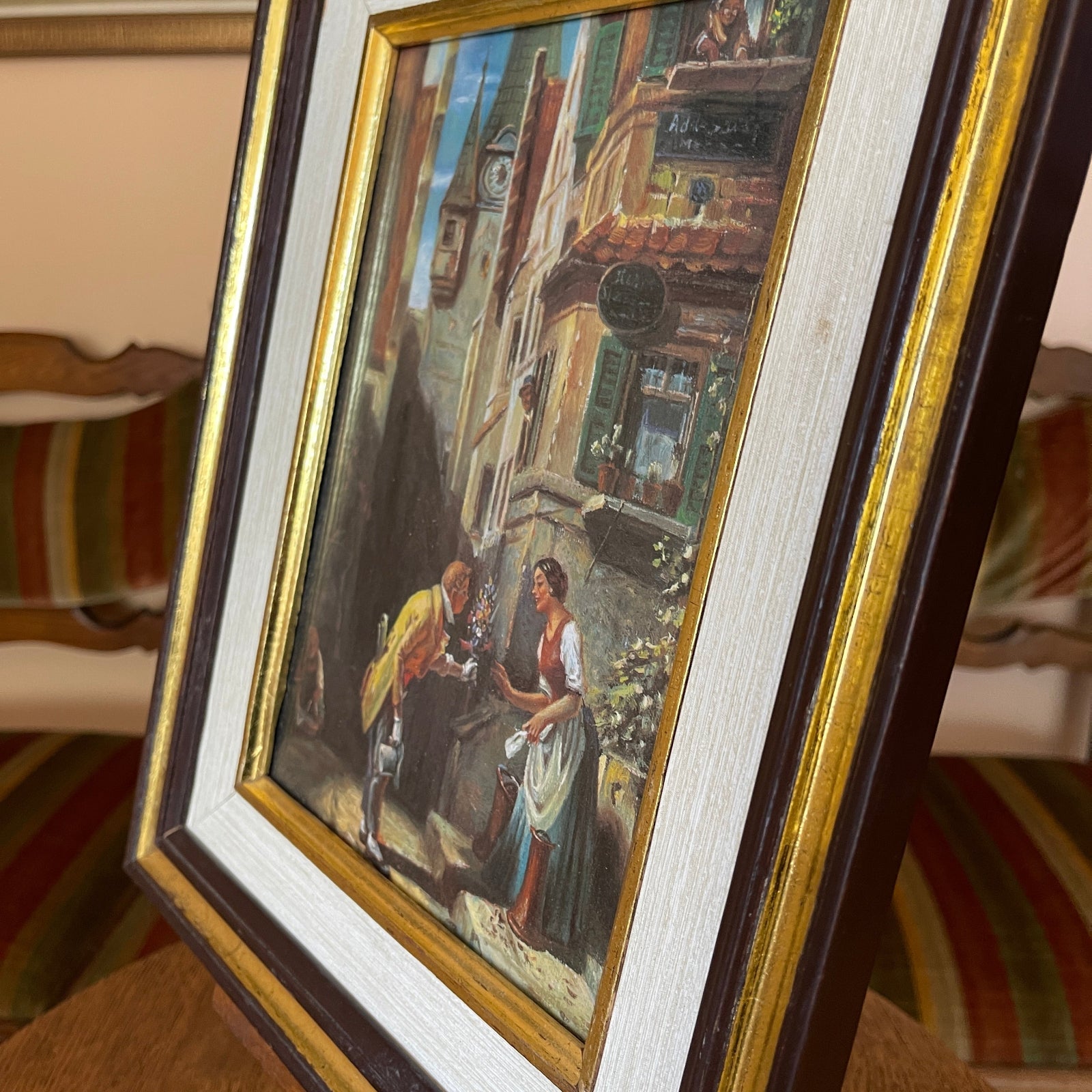 Framed painting of two people in a street scene with architectural details.