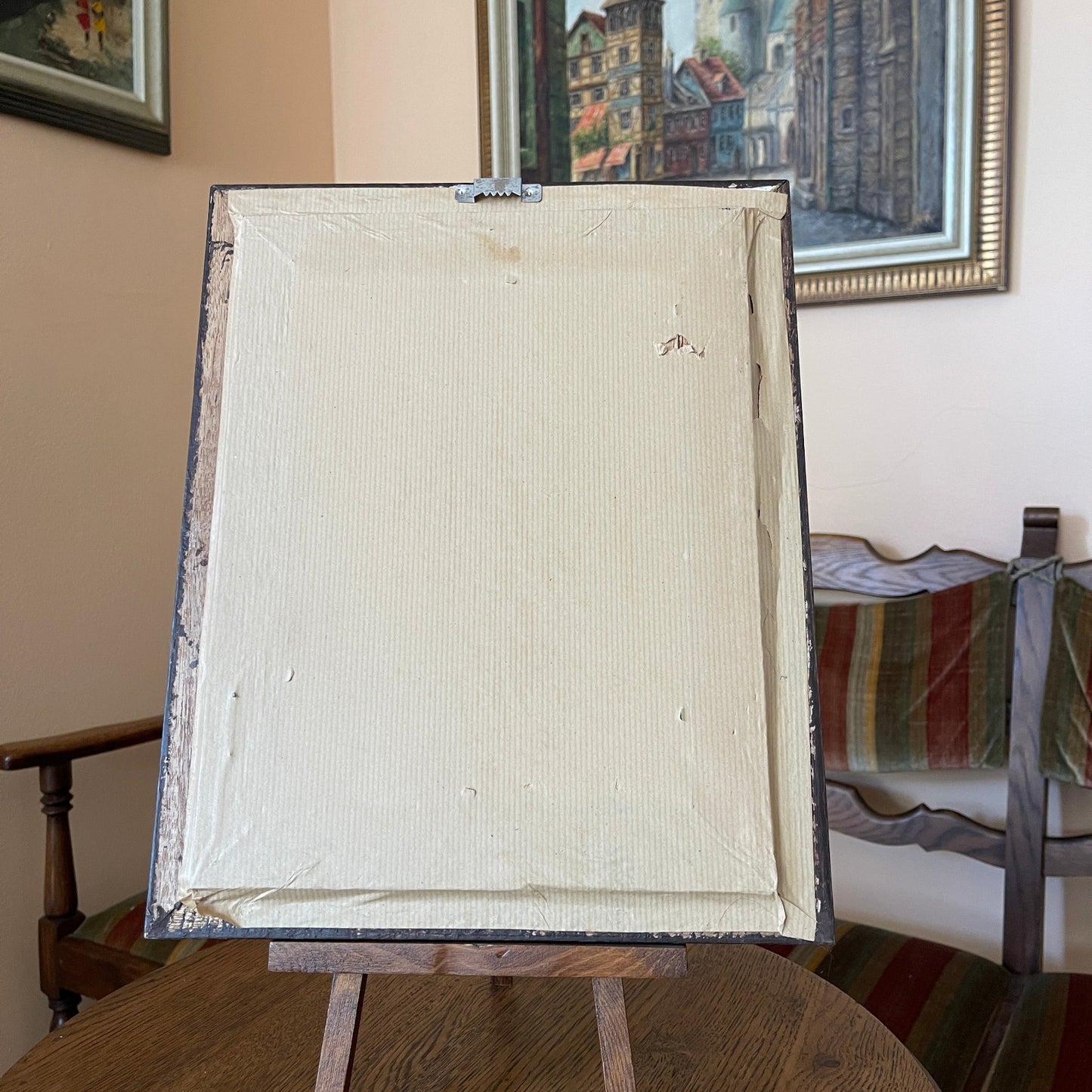 Blank canvas on an easel with a painting in the background