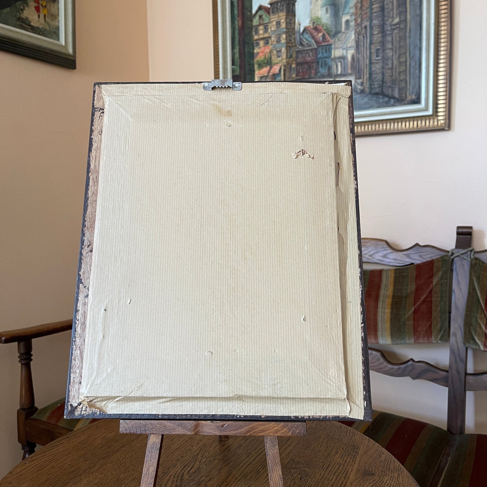 Blank canvas on an easel with a painting in the background
