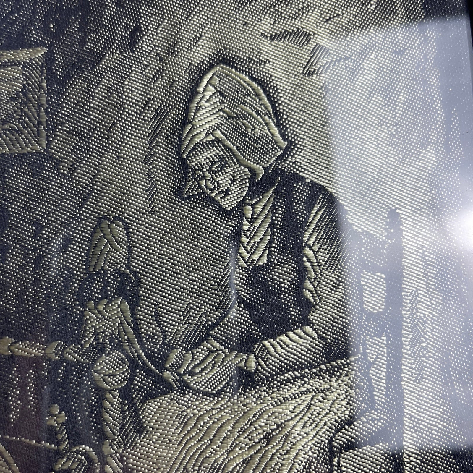 Embroidered design on fabric with a person wearing a hat and scarf.