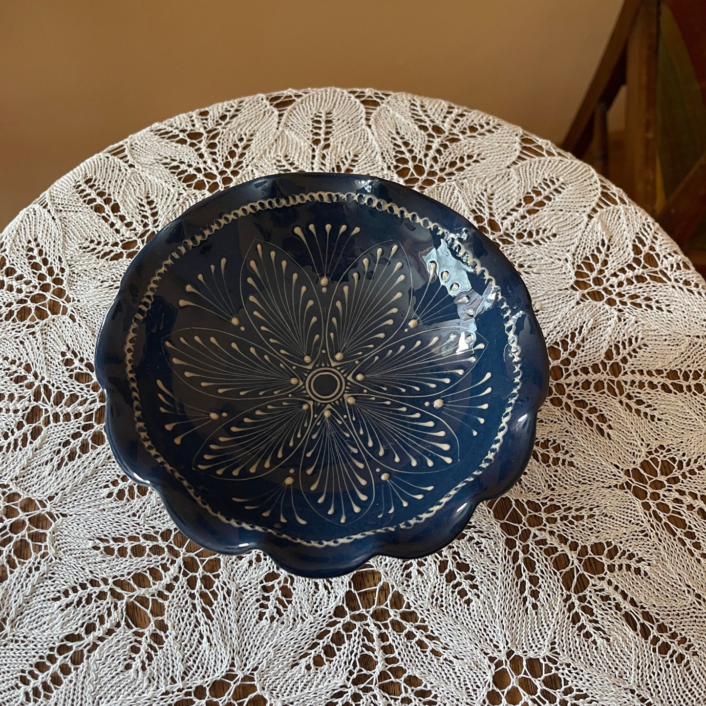 Decorative blue ceramic plate with intricate patterns on a lace tablecloth