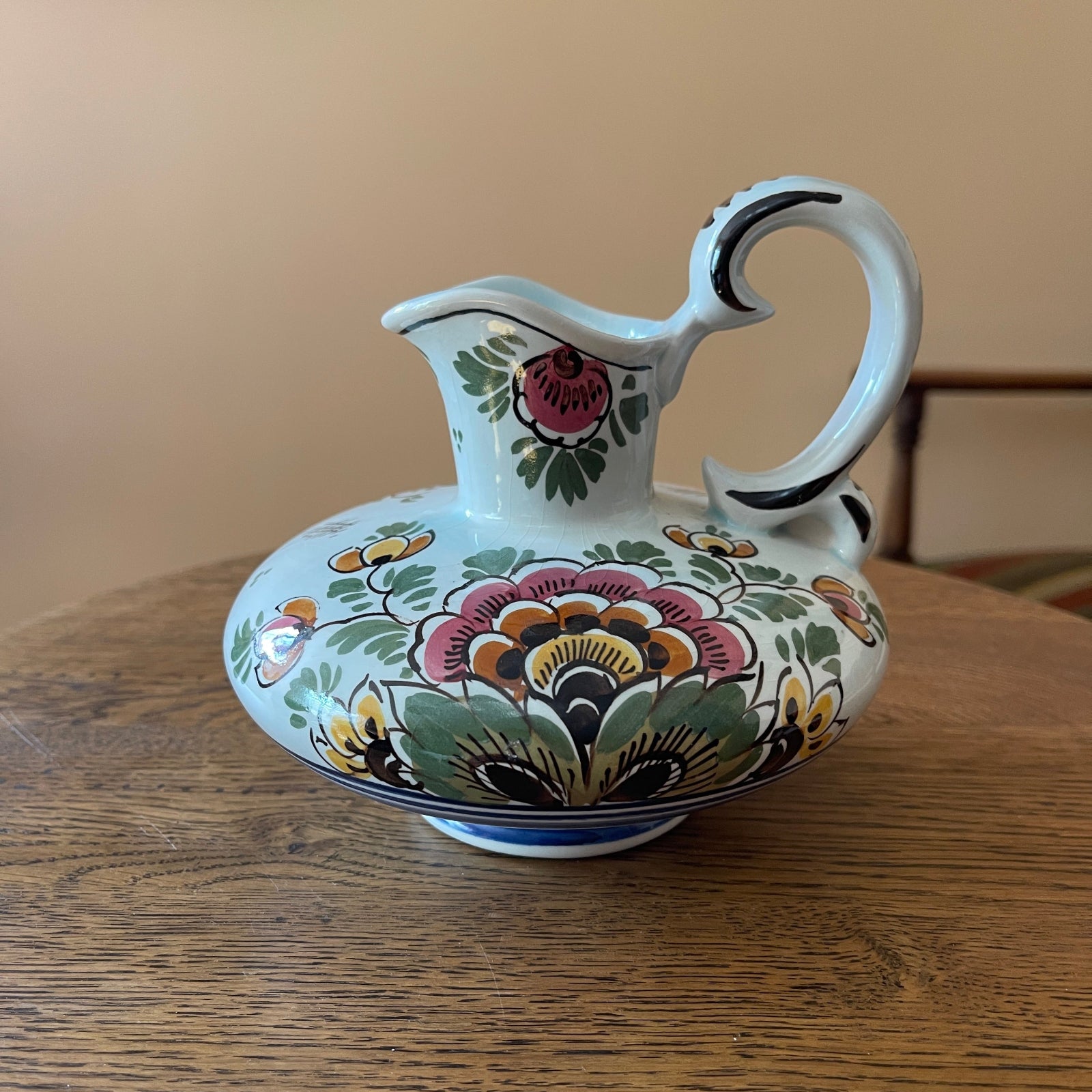 Decorative ceramic pitcher with floral patterns on a wooden surface