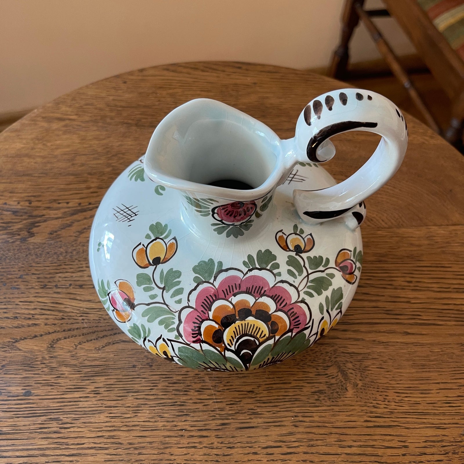 Decorative ceramic pitcher with floral patterns on a wooden surface