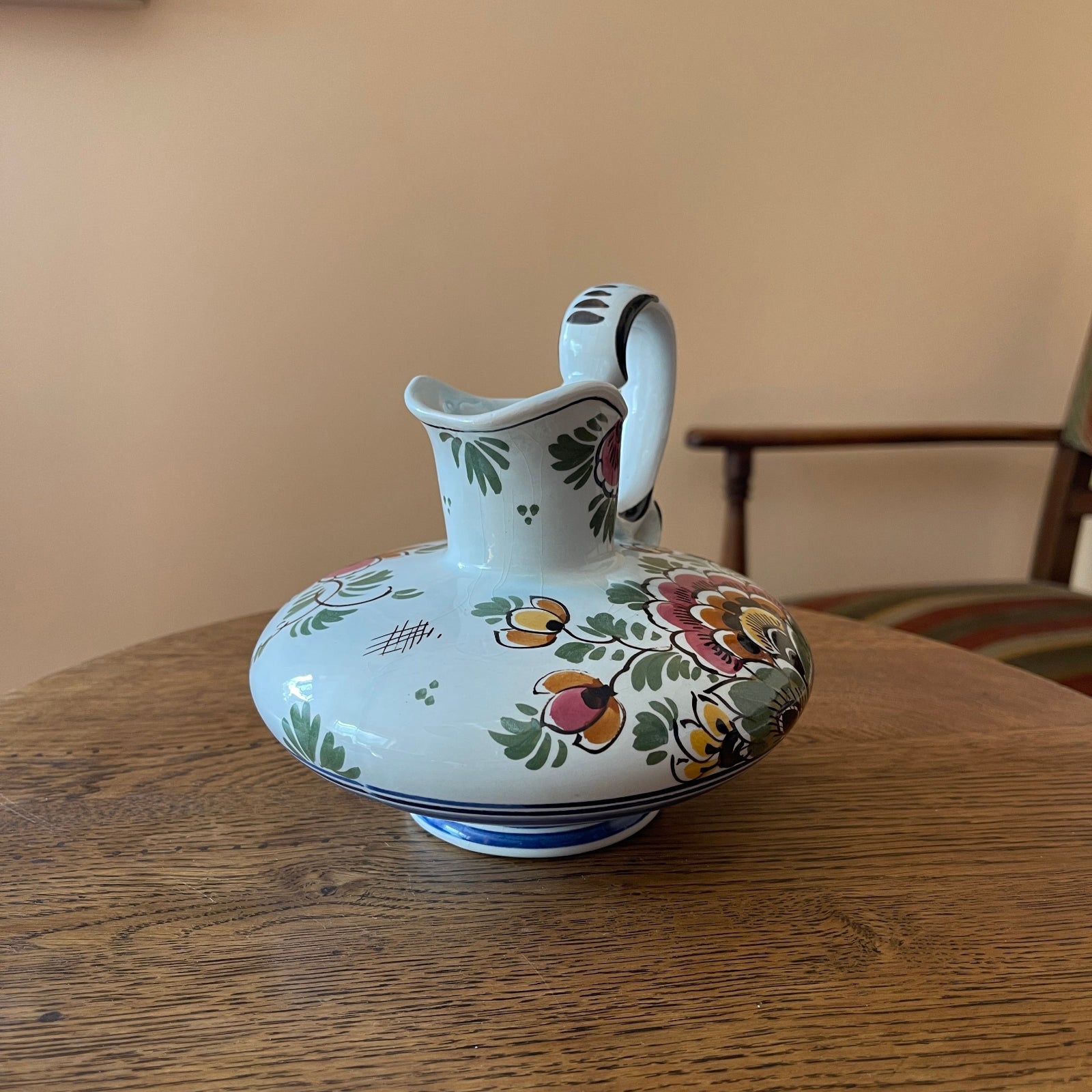Decorative ceramic pitcher with floral patterns on a wooden table.