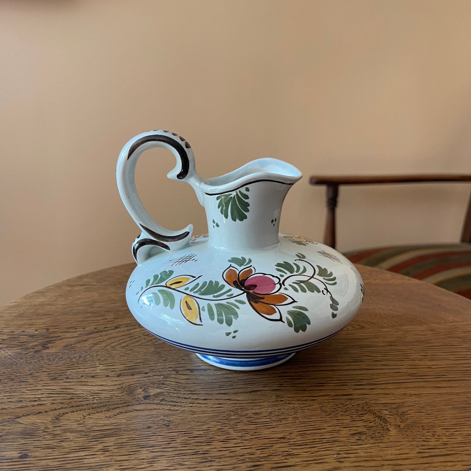 Decorative ceramic pitcher with floral patterns on a wooden table.