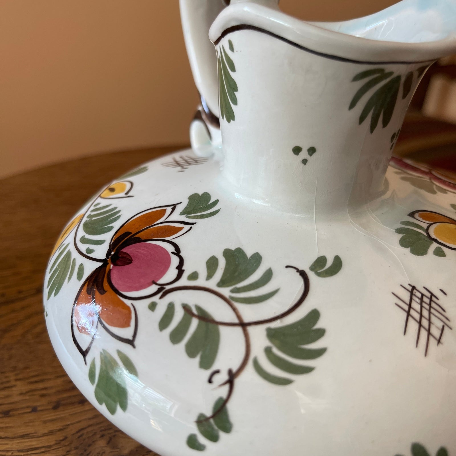 Ceramic pitcher with floral patterns on a wooden surface