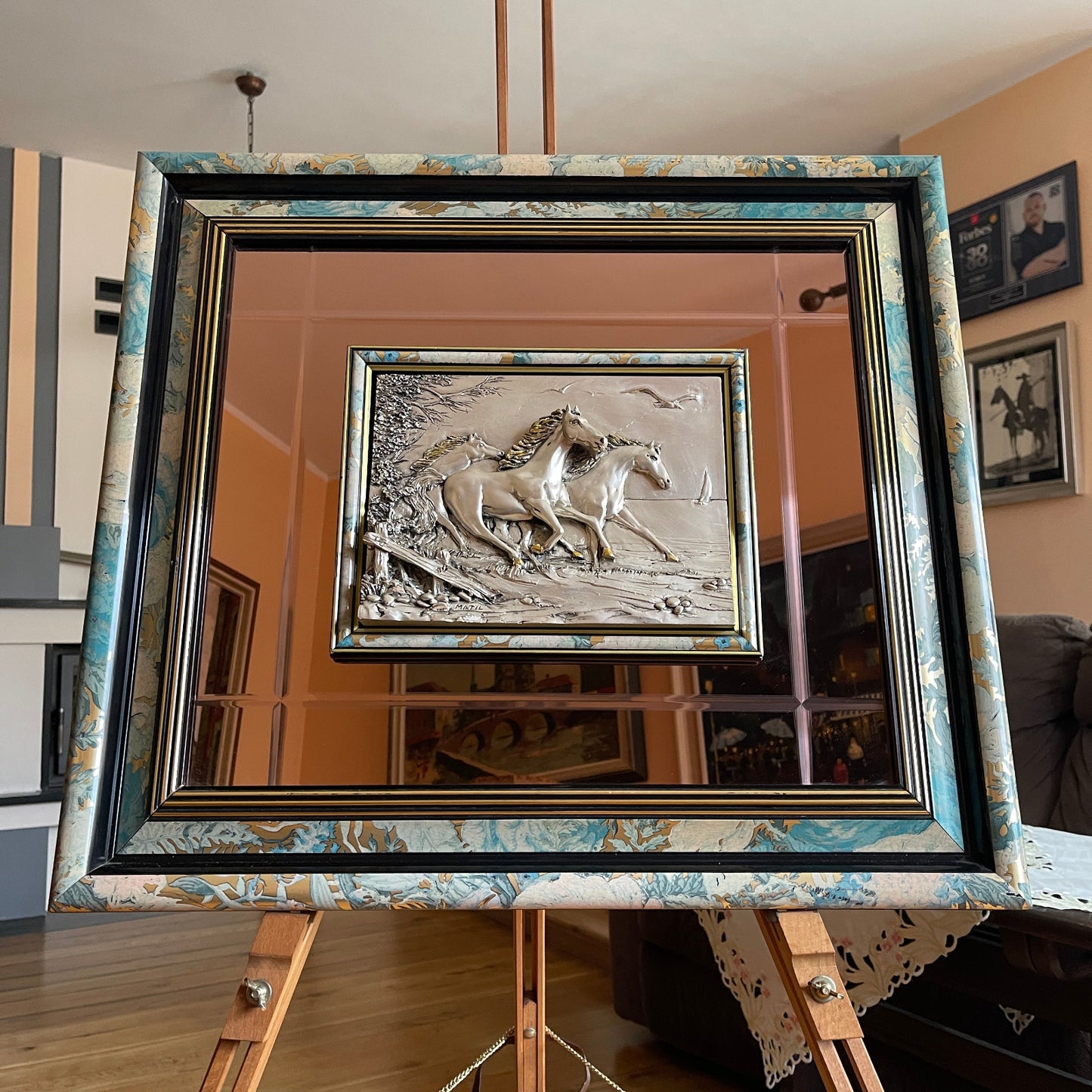 Framed artwork of two horses on a mirror with a decorative frame.