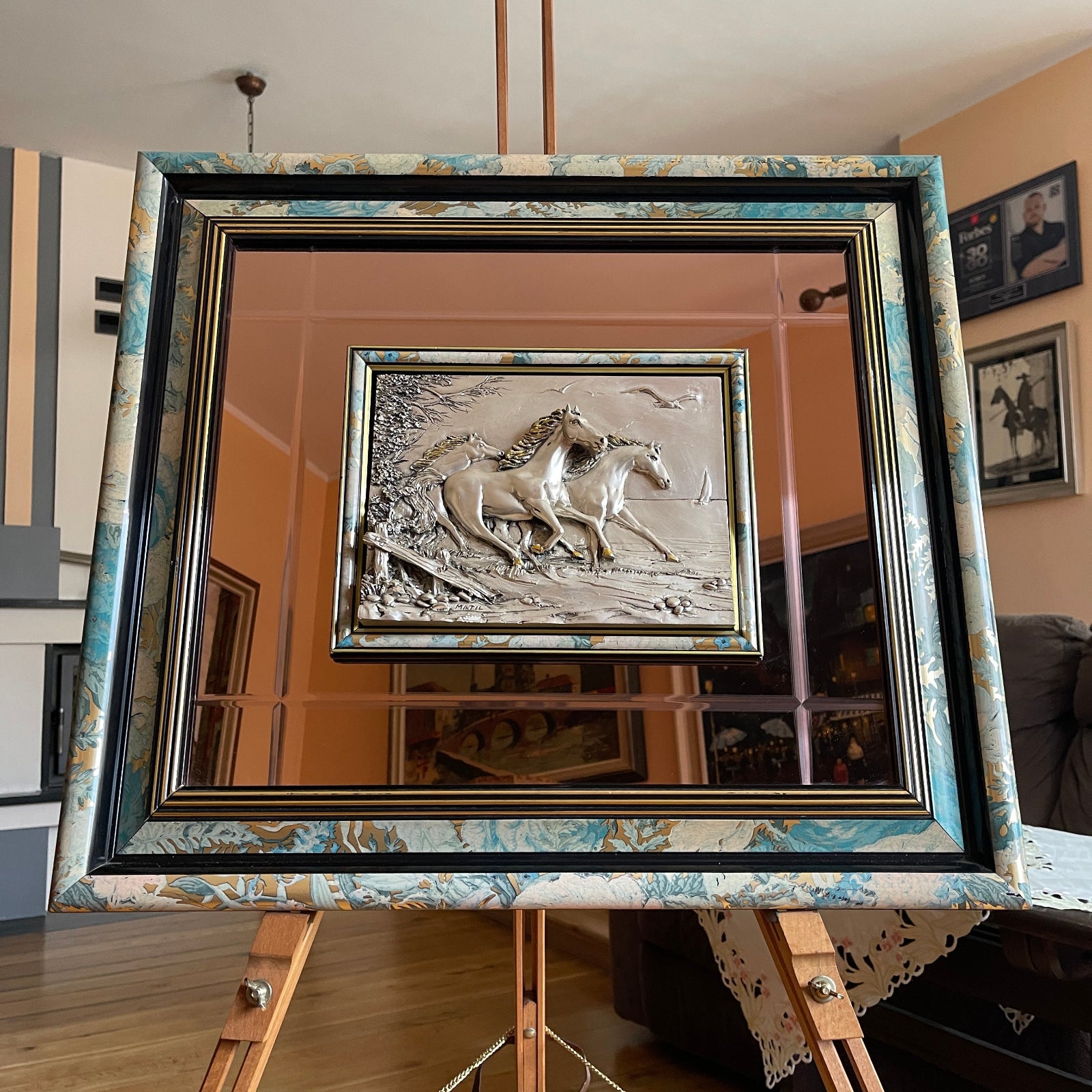 Framed artwork of two horses on a mirror with a decorative frame.