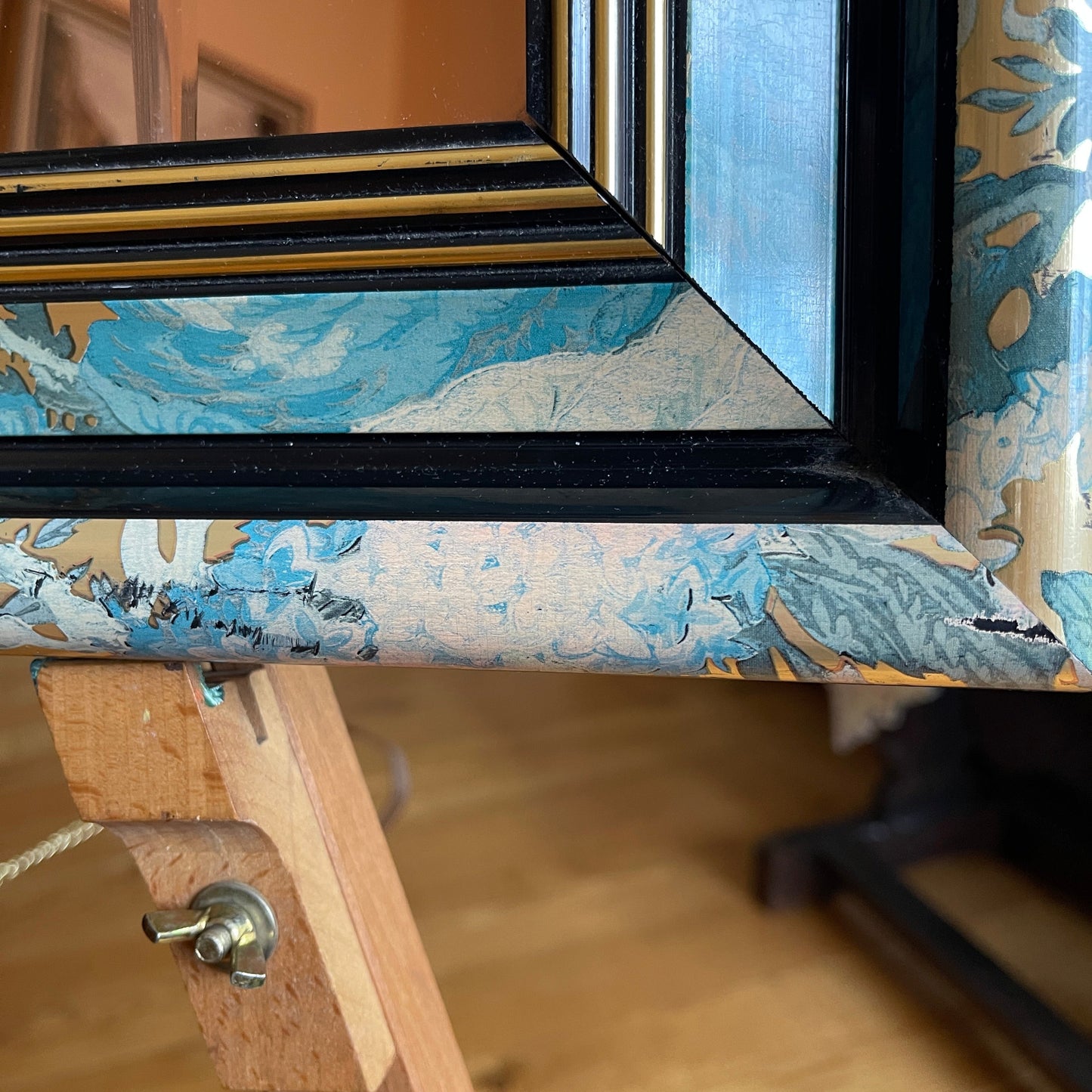 Framed artwork with a blue and gold abstract design on a wooden easel.