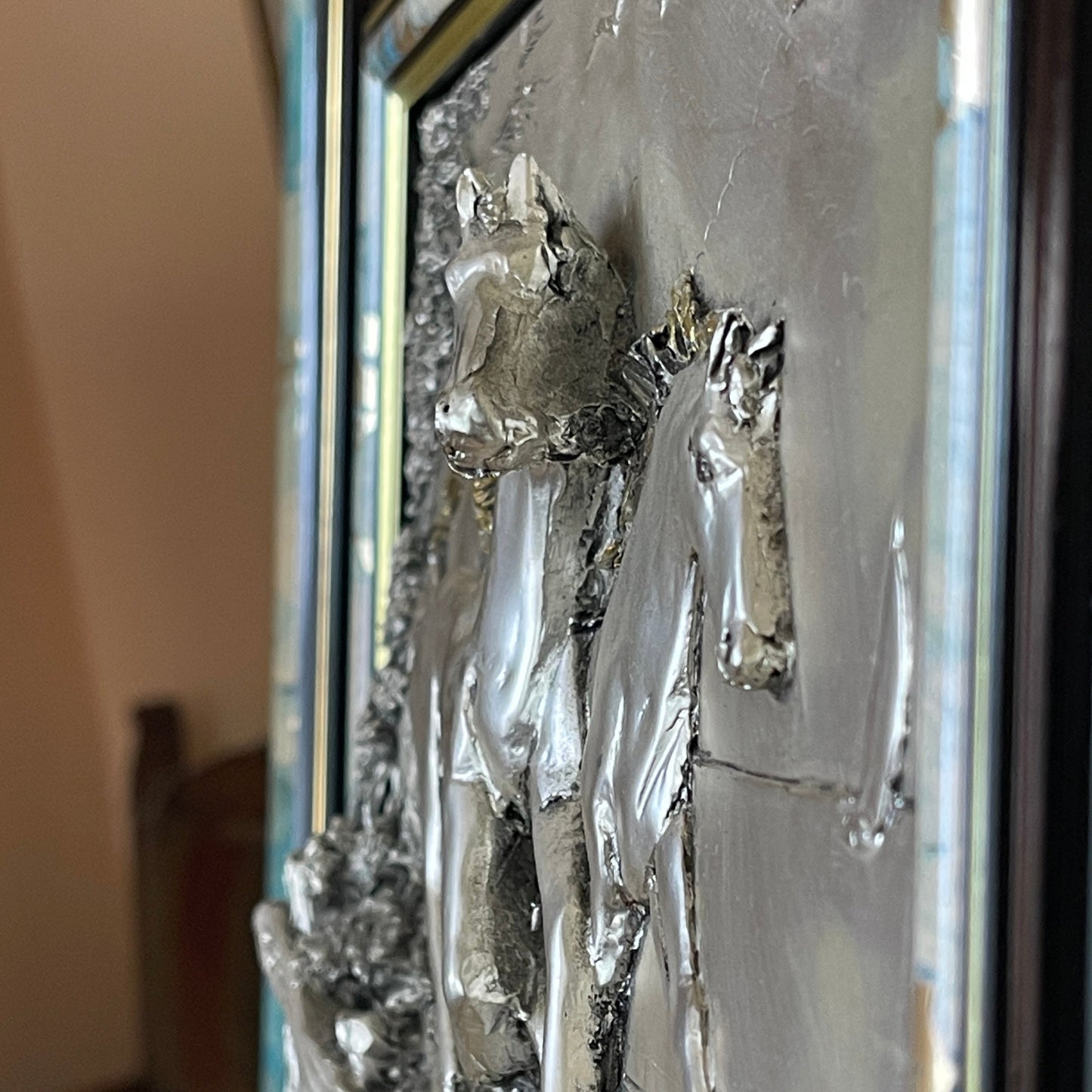 Decorative wall art with horse figures in a metallic finish on a neutral background