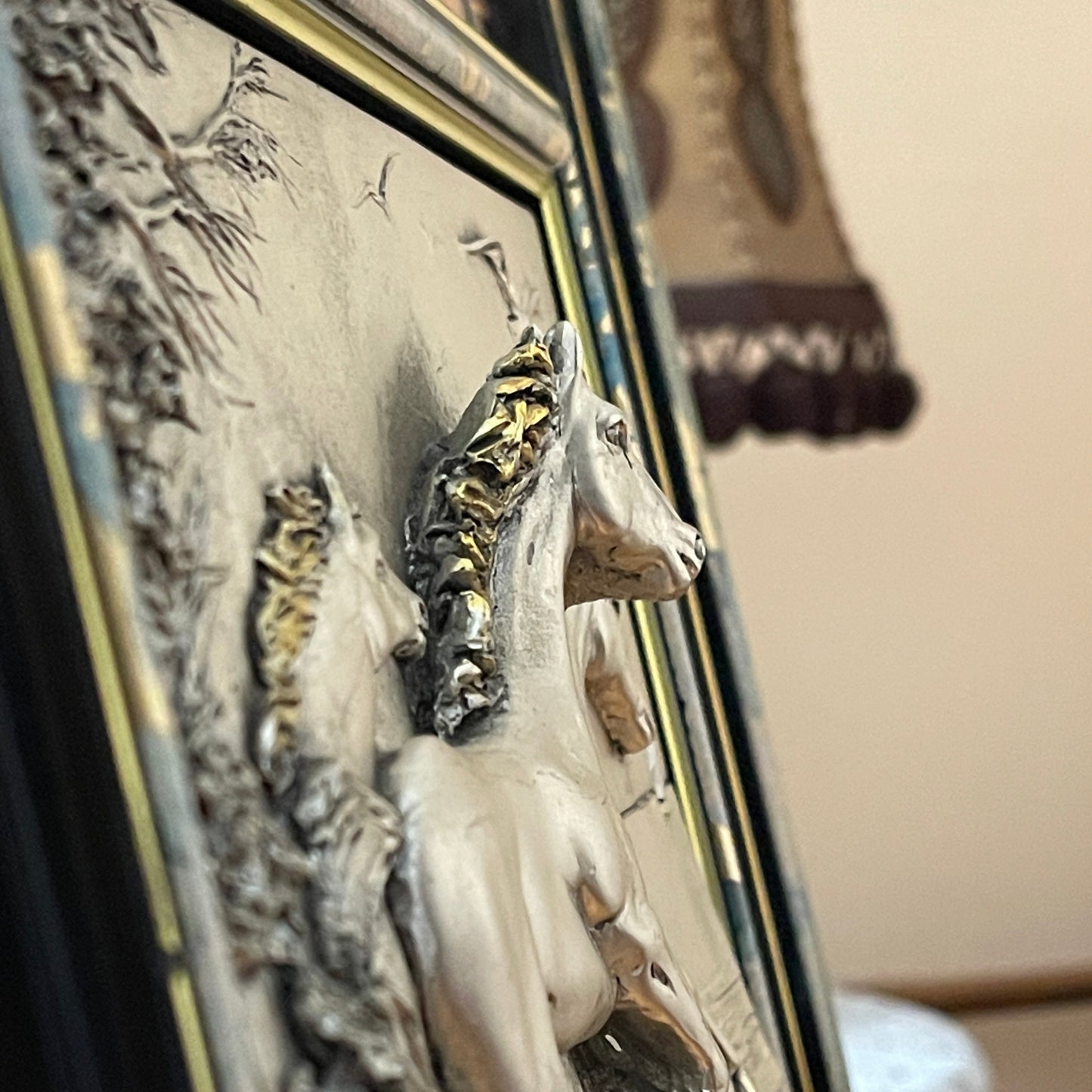 Decorative plaque with a horse design in a gold frame.
