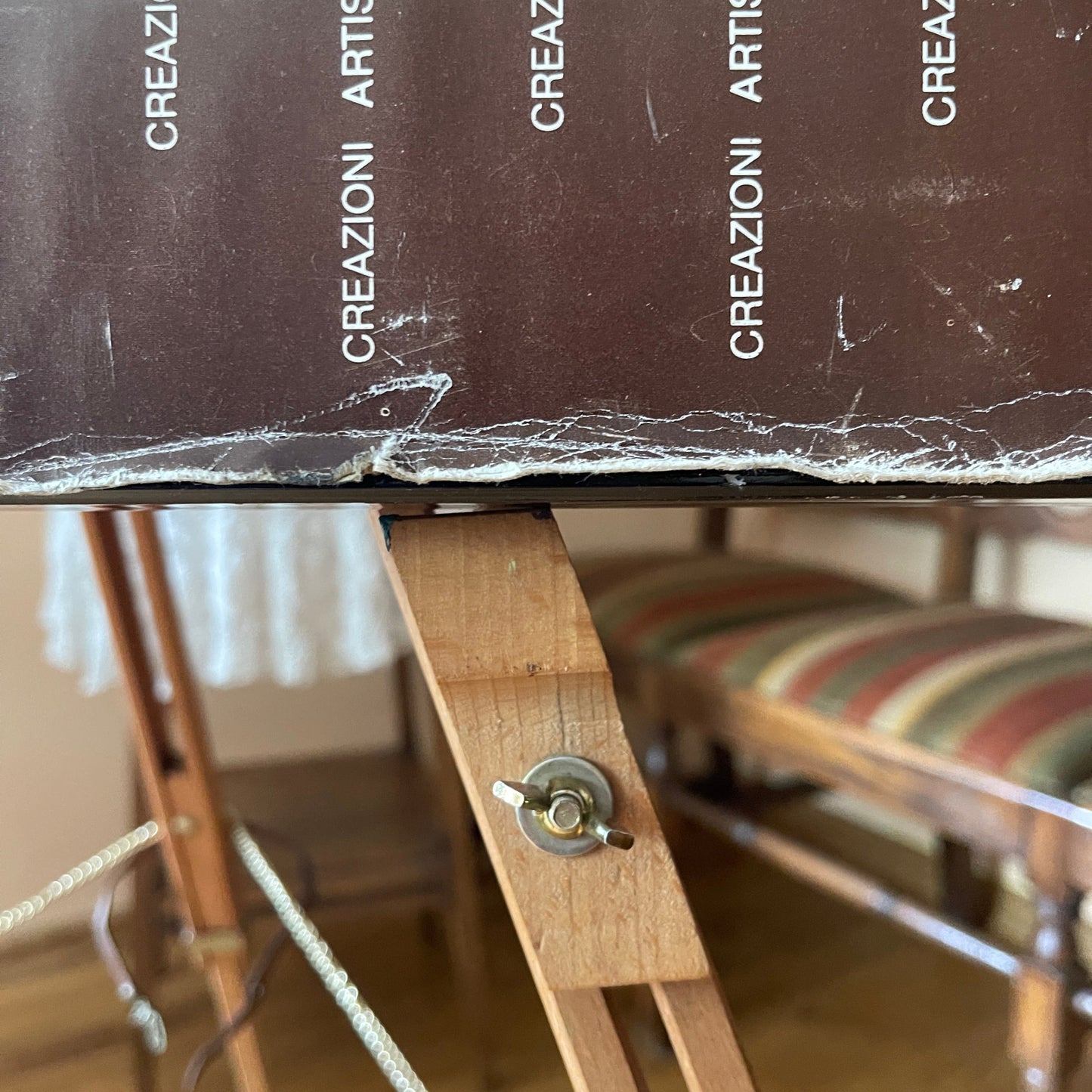 Wooden easel with a black canvas displaying 'CREAZIONI ARTISTICHE' text.