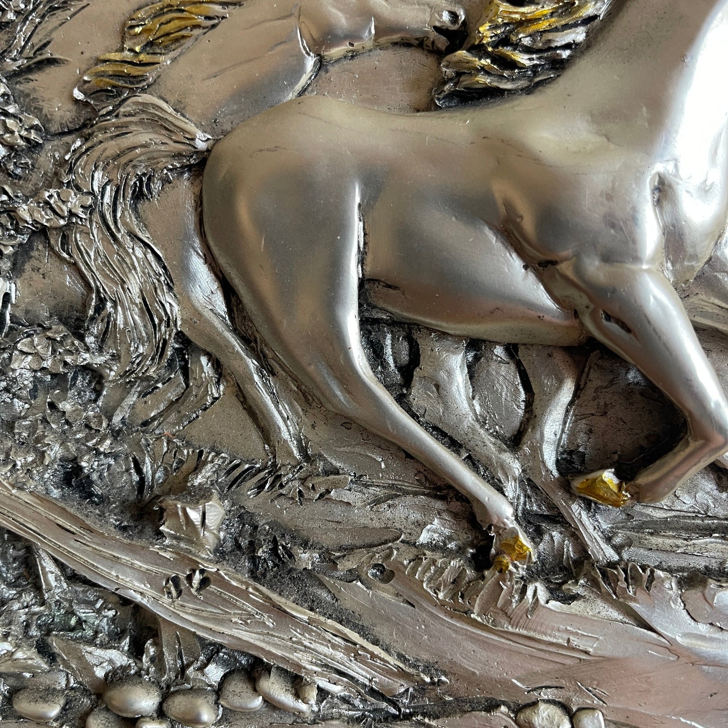 Metallic sculpture of a winged horse on a textured background