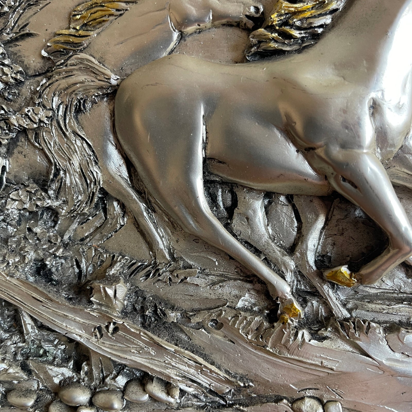 Metallic sculpture of a winged horse on a textured background