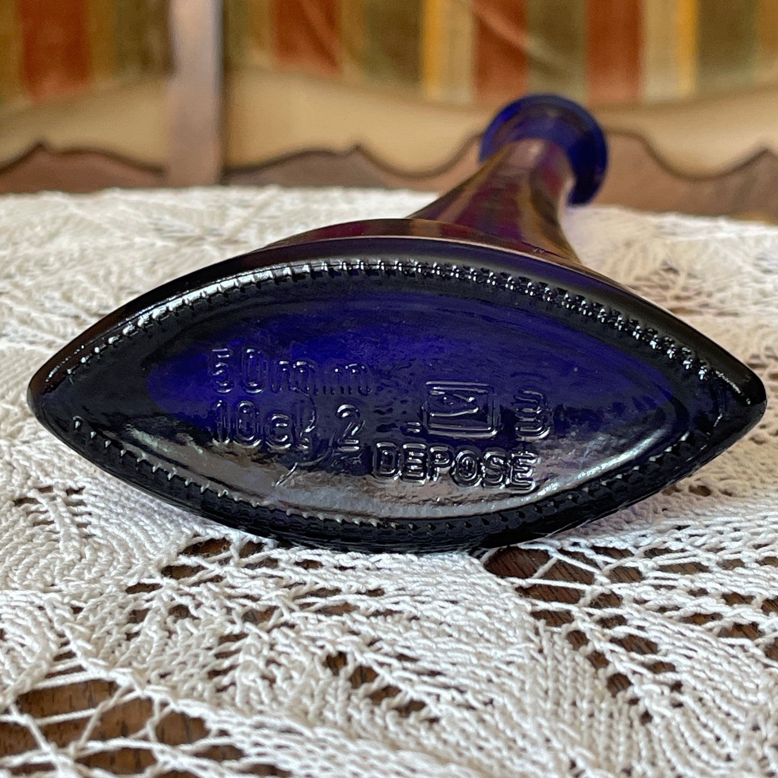 Blue glass bottle cap on a lace tablecloth with a blurred background
