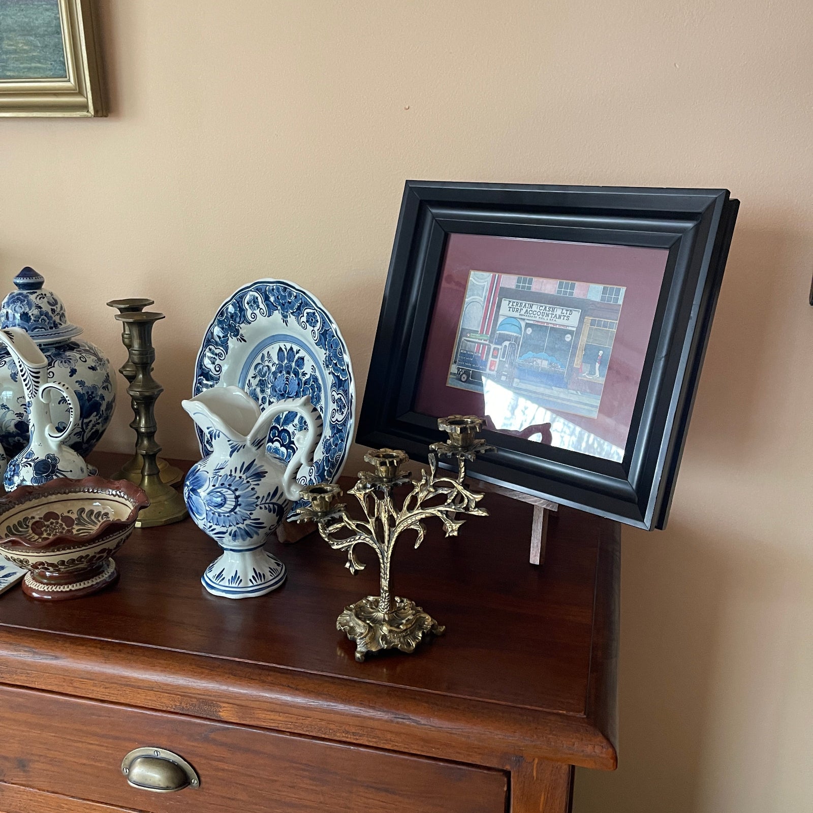 Decorative items including a framed picture, blue and white ceramic pitcher, and other ornaments on a wooden surface.