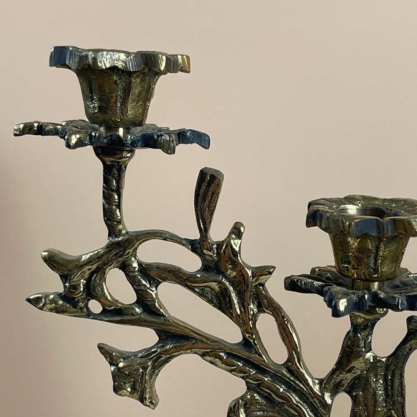 Bronze candle holder with intricate design on a beige background