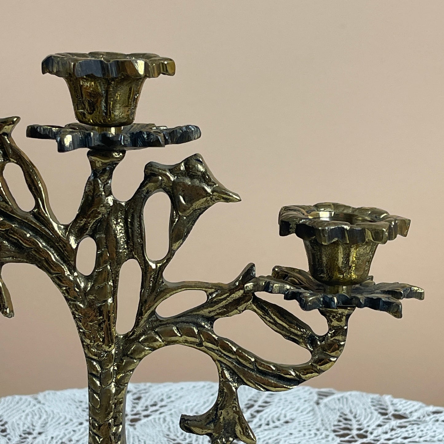 Decorative metal candle holder with bird design on a beige background