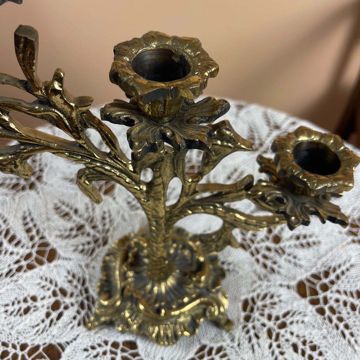 Decorative brass candle holder on a lace surface