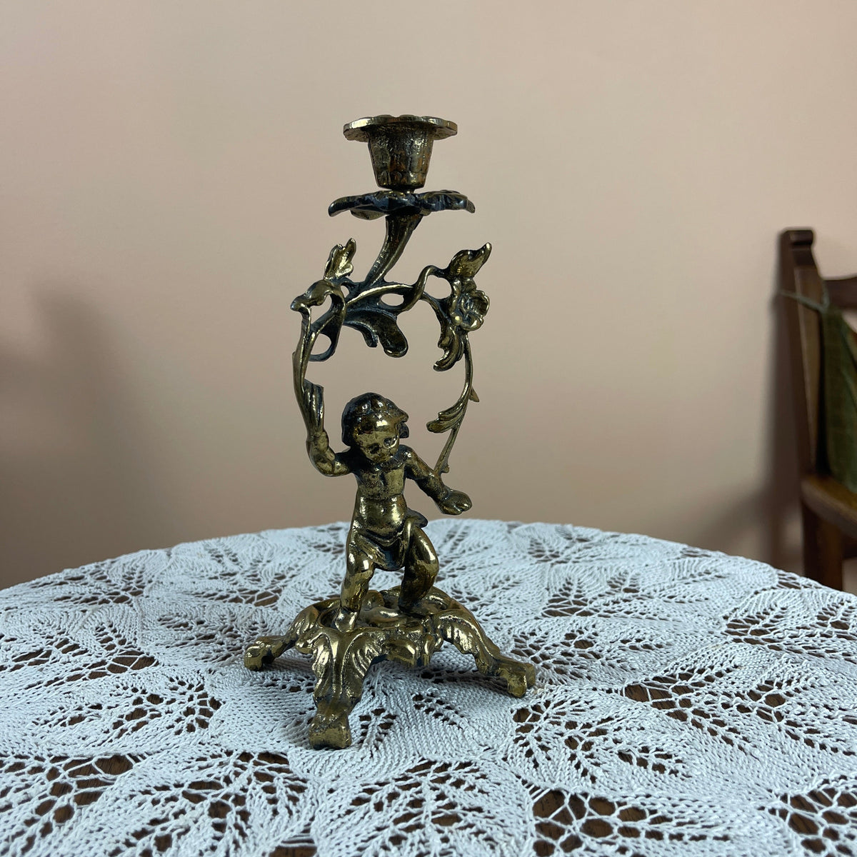 Bronze candle holder with cherub figure on a lace tablecloth