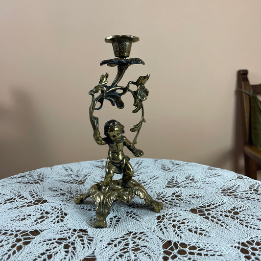 Bronze candle holder with cherub figure on a lace tablecloth