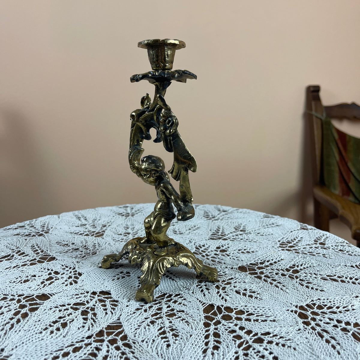 Bronze candle holder on a lace tablecloth with a neutral background