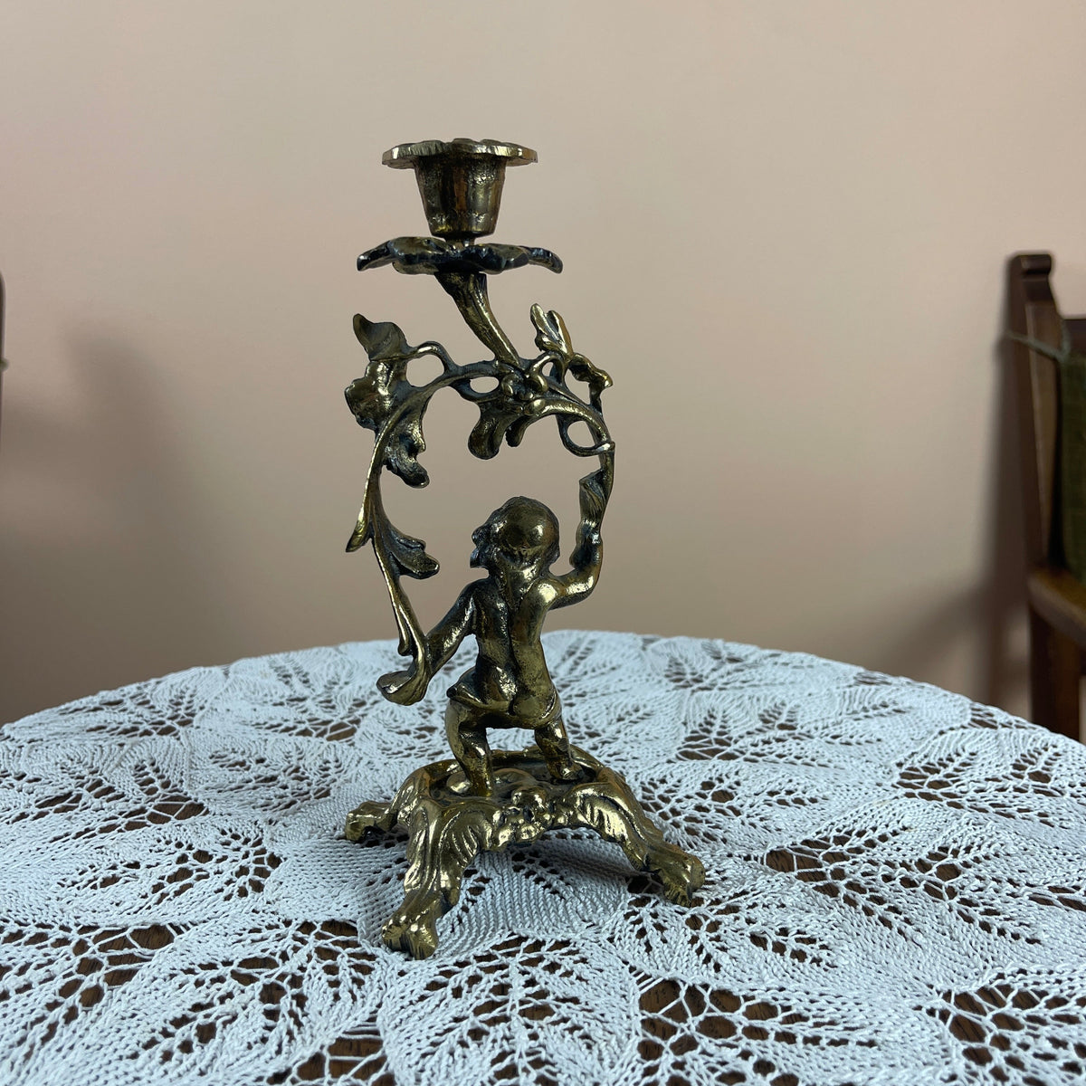 Decorative candle holder with cherub design on a lace tablecloth