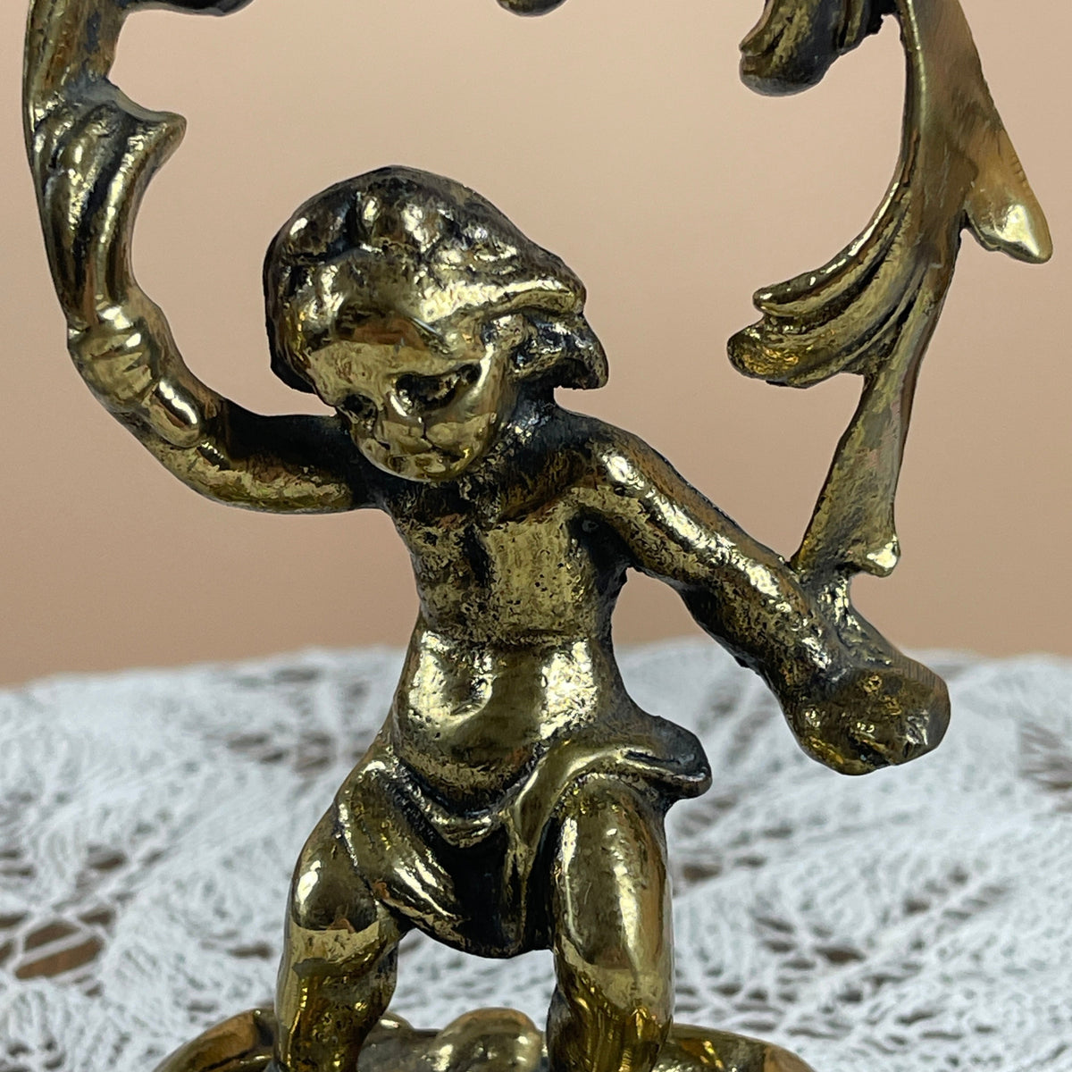 Bronze cherub figurine with wings on a textured surface